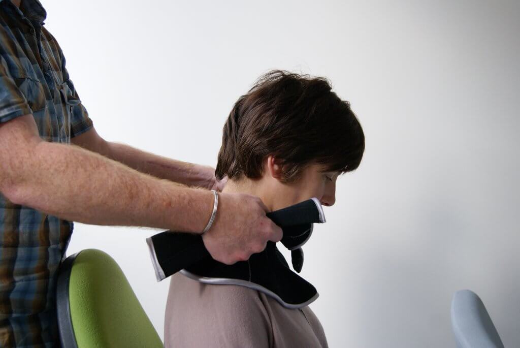 A lady is sitting down and is testing one iteration by having a prototype fitted by one of the design team.