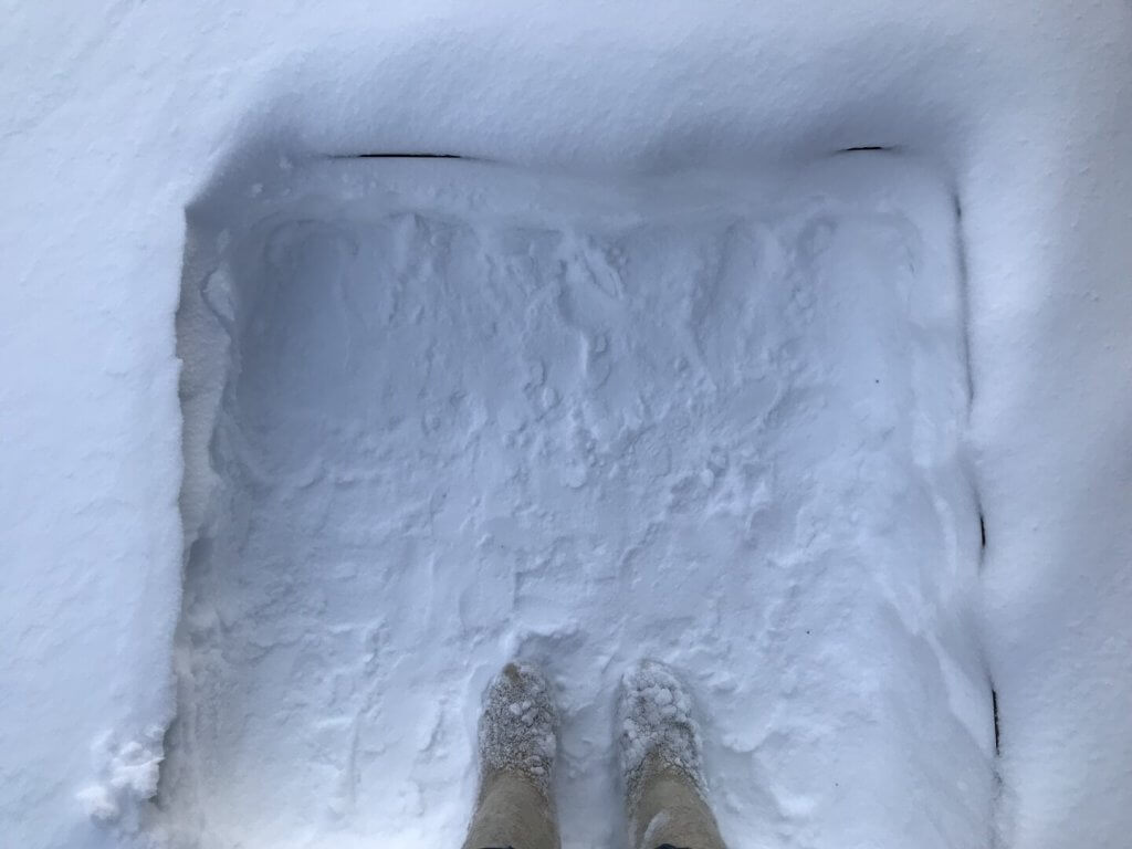 Photograph. The photograph shows Kaisu's point of view looking down at her feet in snowboots, standing in the trampled snow.