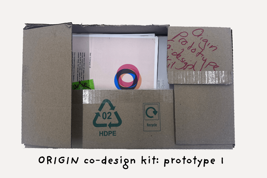 An old carboard box containing various elements of the ORIGIN Co-Design Kit.